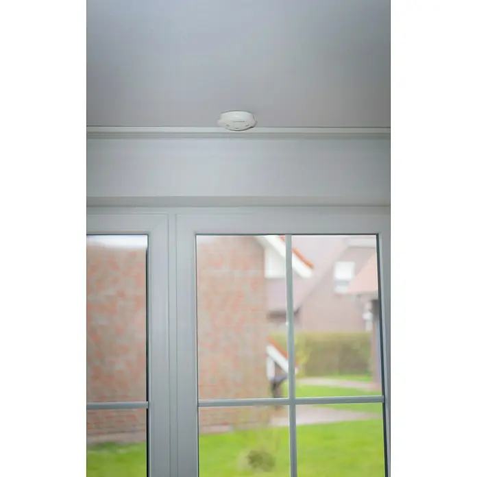 Homematic IP Sistema de alarma HmIP-ASIR-2 -  - Una vista cercana de un detector de humo blanco en un techo blanco, que ofrece seguridad y protección en un hogar.