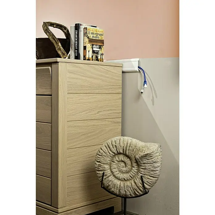 Wandleiste CW 13 - 200 x 1,6 x 8 cm, Weiß, Extrudiertes HD-Polymer - Schrank mit fünf Schubladen aus hellem Holz. Auf dem Schrank liegen Bücher und ein Stück Holz, während eine große Ammonit-Fossilie daneben steht.