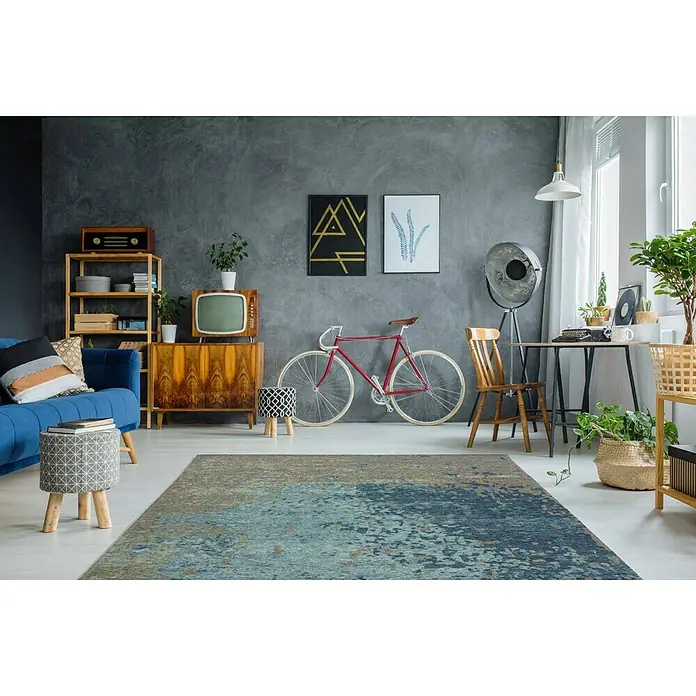 Kayoom Flachgewebeteppich Blaze - Blau/Braun, 230 x 155 cm, 74 % Polyester - Ein stilvoller Wohnraum mit einem blauen Sofa, einem Teppich mit abstraktem Muster und einem Vintage-TV, der eine gemütliche Atmosphäre schafft.