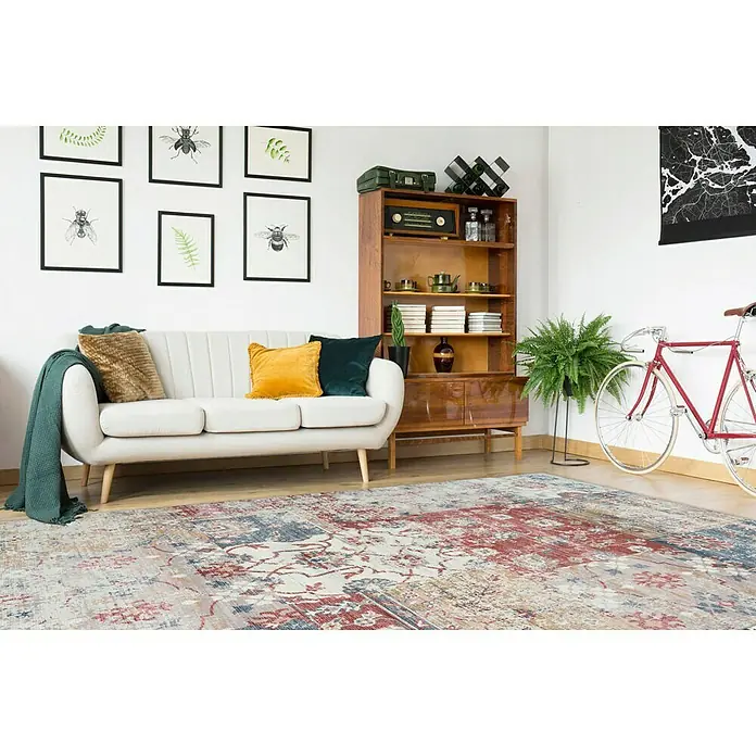 Kayoom Kurzflorteppich IndianaMulti, 170 x 120 cm, 100 % Baumwolle - Ein einladendes Wohnzimmer mit einem stilvollen Teppich, einem cremefarbenen Sofa und einem Bücherregal aus Holz.