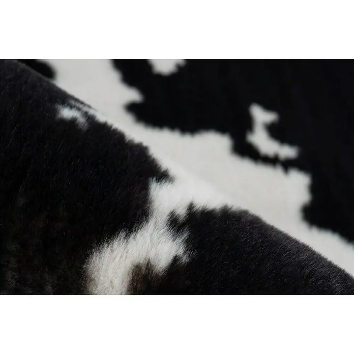 Kayoom Hochflorteppich Kuh - Weiß/Schwarz, 160 x 120 cm, 100 % Polyester - Nahaufnahme eines Kuhfellteppichs mit schwarz-weißem Muster, das eine weiche und luxuriöse Textur zeigt.