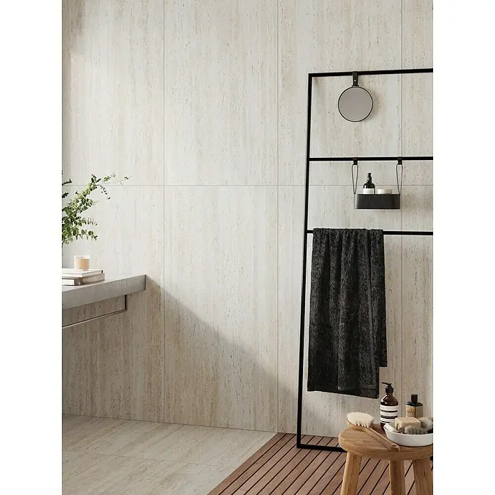 Atlas Concorde Solution Feinsteinzeugfliese Pompei Bianco Romano - 60 x 120 cm, Weiß, Matt - Badezimmer-Interieur mit Fokus auf einem Handtuchhalter mit Handtuch, Spiegel und Ablage, neben einem Hocker mit Badutensilien.