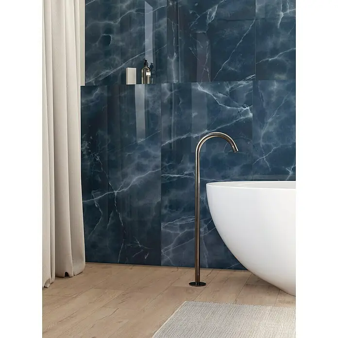 Atlas Concorde Solution Marble Vison Feinsteinzeugfliese Onice Blue - 60 x 120 cm, Blau, Glänzend - Elegantes Badezimmer mit blauen Marmorfliesen, freistehender Badewanne und stilvoller Armatur.