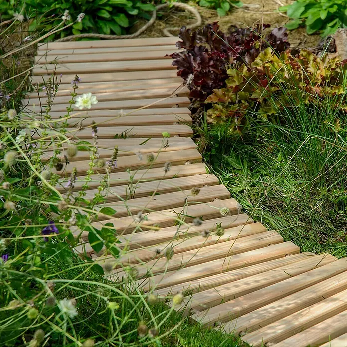 Dobar Gartenweg Mobil - L x B x H: 195 x 36 x 2 cm, Transportfähig - Detailaufnahme eines gewundenen Holzstegs in einem Garten, umgeben von üppigem Grün und bunten Pflanzen. Die Holzstruktur ist gut sichtbar.