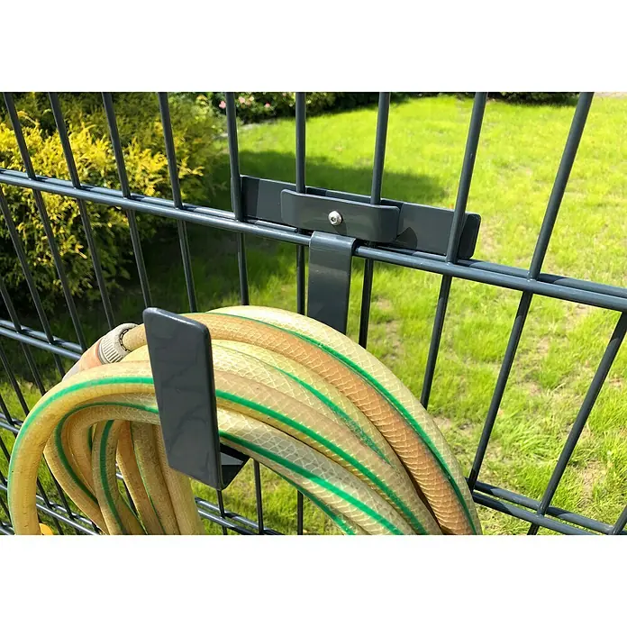 WMT Eindrehhalterung als Schlauchhalter - Anthrazit - Gartenschlauch hängt an einem grauen Schlauchhalter, der an einem Zaun befestigt ist. Der Schlauch ist gelb mit grünen Streifen.