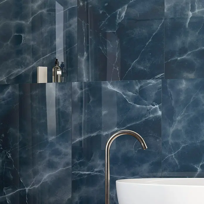 Atlas Concorde Solution Marble Vison Feinsteinzeugfliese Onice Blue - 60 x 120 cm, Blau, Glänzend - Nahaufnahme einer eleganten blauen Marmorwand mit Armatur, die ein luxuriöses und modernes Badezimmerambiente schafft.