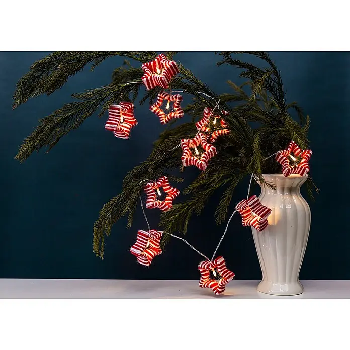 Tween Light LED-Lichterkette Sterne - Innen, Anzahl Leuchtmittel: 10 Stk., Batteriebetrieben - Weihnachtliche Sternenlichterkette mit rot-weißen Sternen, drapiert um einen Zweig in einer weißen Vase, die festliche Stimmung verbreitet.