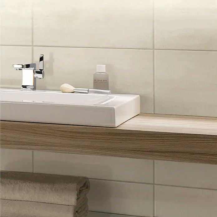 Wandfliese Leyre Arena Beige - 30 x 60 cm, Beige, Glänzend - Modernes Badezimmerwaschbecken mit Armatur, Pinsel, Lotion und einem hellen Holzregal. Handtücher liegen darunter bereit.