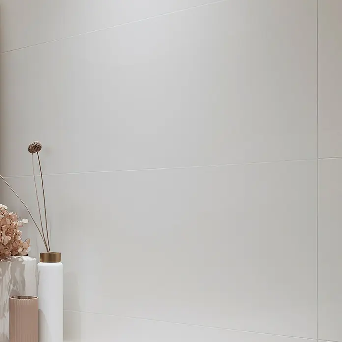 Wandfliese White Satin - 40 x 120 cm, Weiß, Matt - Ein minimalistisches Interieur mit einer hellgrauen Wand, geschmückt mit dezenten Deko-Objekten, die eine ruhige Atmosphäre schaffen.