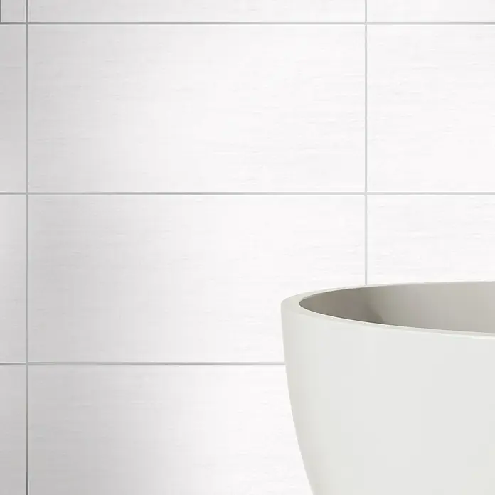 Wandfliese Eifel New - 30 x 60 cm, Weiß, Matt - Moderne weiße Badewanne vor einer weißen gefliesten Wand, die Eleganz und Komfort im Badezimmerdesign bietet.