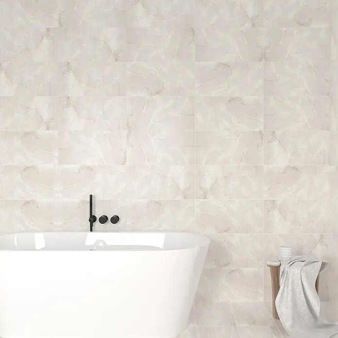 Wandfliese Trentino - 30 x 60 cm, Grau/Weiß, Glänzend - Nahaufnahme eines Badezimmers mit weißen Marmorfliesen, einer freistehenden Badewanne und einem kleinen Holzhocker.