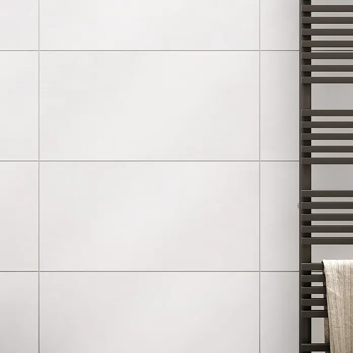 Wandfliese Zürich New - 30 x 60 cm, Weiß, Matt - Nahaufnahme eines modernen, beheizbaren Handtuchhalters an einer weißen gefliesten Wand, der Funktionalität und Stil im Badezimmer vereint.