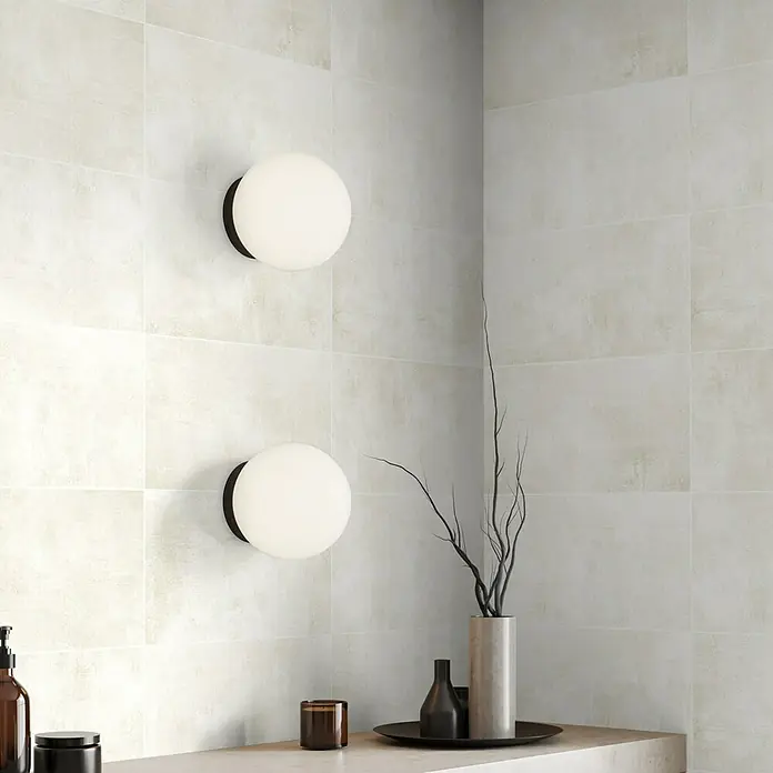 Wandfliese Casa - 29,7 x 59,7 cm, Beige, Matt - Wandleuchten mit weißen Kugellampen und dunklen Fassungen an einer beigen Fliesenwand. Dekorative Elemente ergänzen das minimalistische Design.