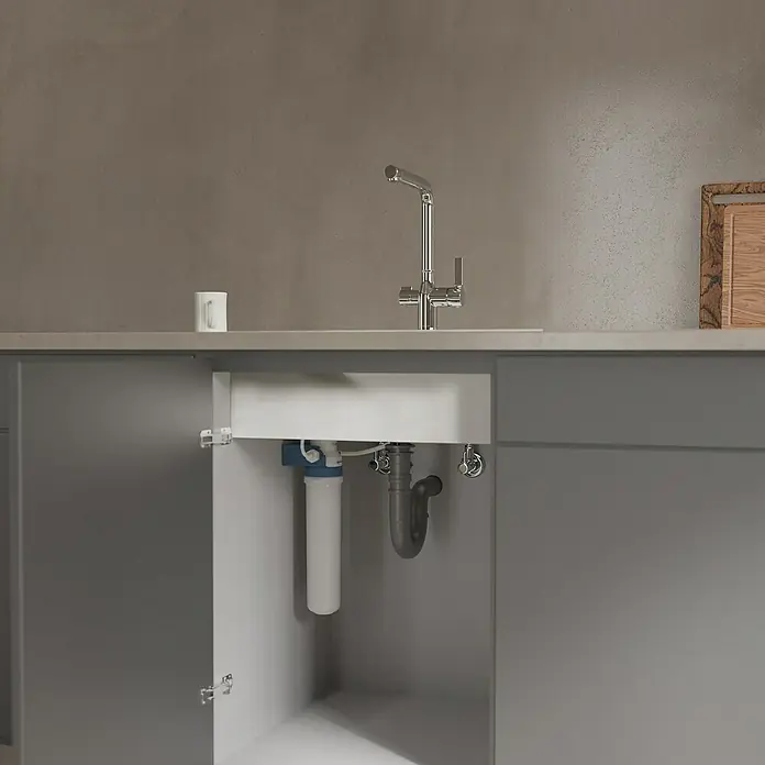 Camargue Spültischarmatur Blueperl - Chrom, Glänzend - Nahaufnahme eines Spültischunterschranks, der einen Wasserfilter und die zugehörigen Rohre zeigt.