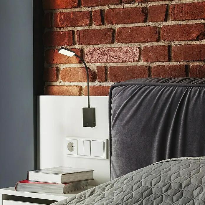 Briloner LED-Leseleuchte Cielo - Höhe: 56 cm, Schwarz - Nahaufnahme einer modernen LED-Wandleuchte mit flexiblem Arm, montiert an einer Nachttischkonsole neben dem Bett für optimale Beleuchtung.