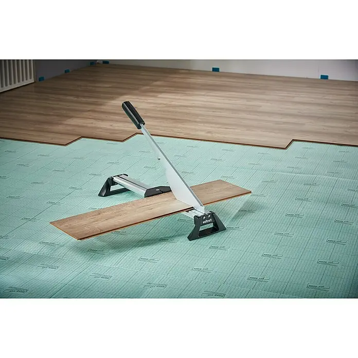 Wolfcraft Laminatschneider LC 600 - Geeignet für: Laminat, Schnittbreite: 465 mm, Material: Aluminium - Laminatschneider im Einsatz auf grüner Unterlage, Laminatboden im Hintergrund.