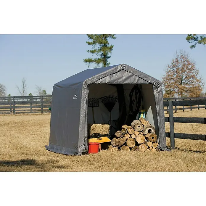 ShelterLogic Gerätehaus - Außenbreite inkl. Dachüberstand: 297 cm, Außentiefe inkl. Dachüberstand: 305 cm, Stahl, Grau - Aufnahme eines grauen ShelterLogic-Lagerschuppens im Freien, der Holz und Gartengeräte schützt.