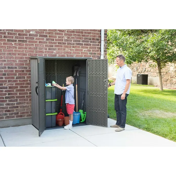 Lifetime Geräteschrank - Außenbreite inkl. Dachüberstand: 136 cm, Außentiefe inkl. Dachüberstand: 70 cm, Kunststoff, Dunkelgrau - Kind und Mann vor einem Gartenschrank. Der Schrank ist mit Gartengeräten gefüllt.