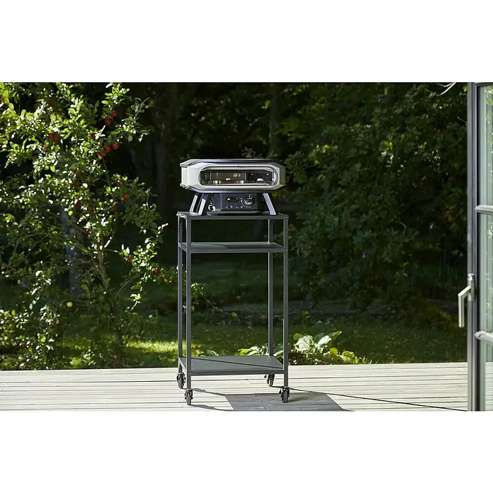 Cozze Pizzaofen Premium 17" - Grillfläche (B x T): 42,5 x 42,5 cm, 8 kW - Ein tragbarer Pizzaofen auf einem Rollwagen im Freien, ideal für Gartenpartys und kulinarische Erlebnisse im Freien.