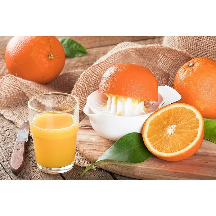 Orangenbaum - Citrus sinensis, 35 l - Frisch gepresster Orangensaft in einem Glas, neben einer halbierten Orange und einer Saftpresse auf einem rustikalen Holztisch.