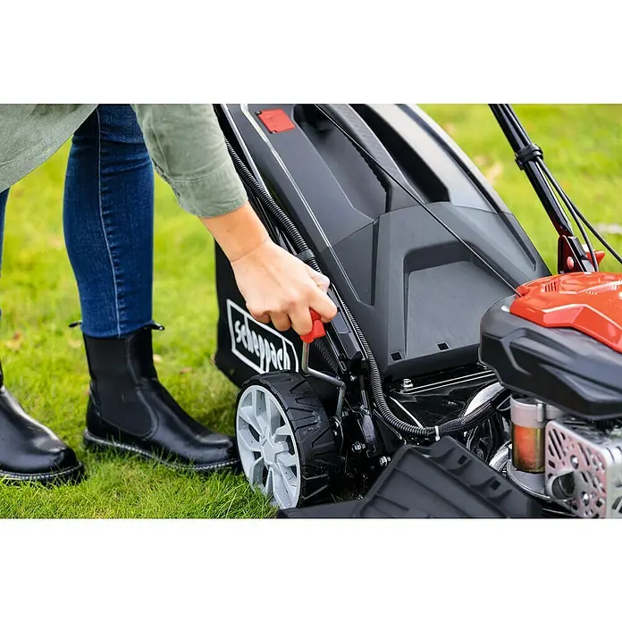Scheppach Benzin-Rasenmäher PML46-150ES - 150 cm³, Schnittbreite: 46 cm, Hybrid-Start: Elektrostart & Seilzugstarter - Nahaufnahme eines Benutzers, der den Scheppach Rasenmäher bedient, mit Fokus auf Bedienelemente und Design.
