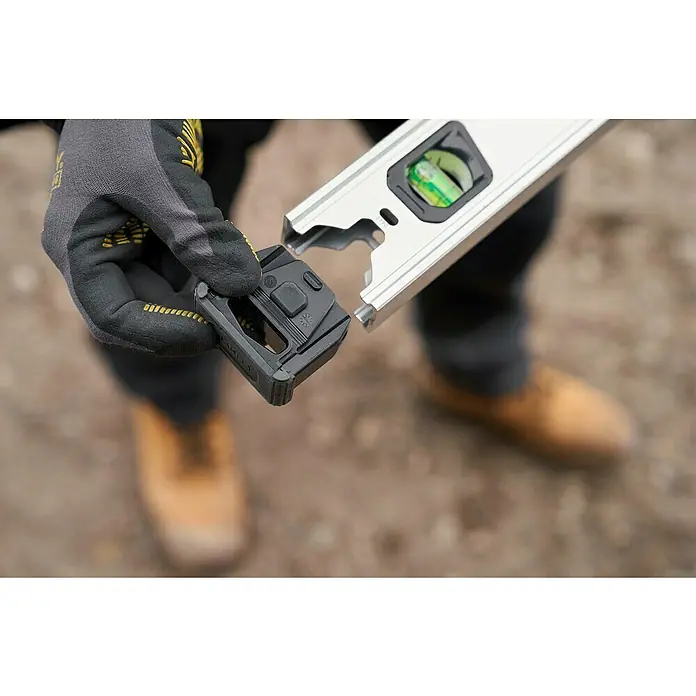 Stanley FatMax Nivel de burbuja Xtreme - Plateado - Un artesano adjunta un dispositivo negro y cuadrado a un nivel de burbuja plateado. Ideal para mediciones precisas en proyectos de construcción.