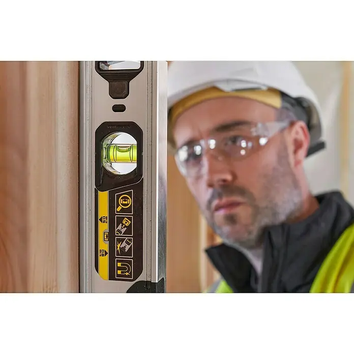 Stanley FatMax Nivel de burbuja Xtreme - Plateado - El trabajador utiliza un nivel de burbuja para verificar la verticalidad de una estructura de madera. La herramienta indica precisión y exactitud.