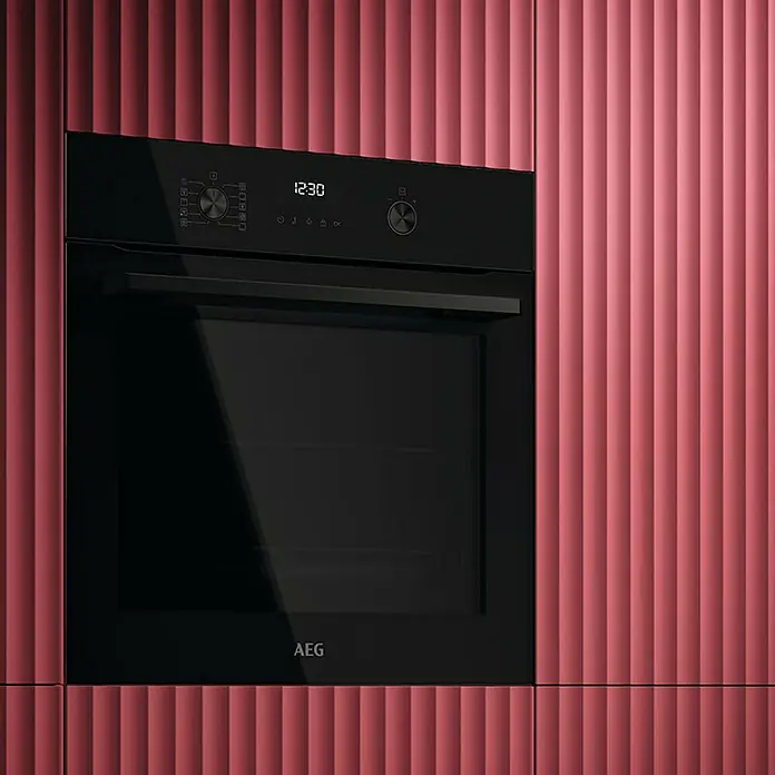 AEG Horno empotrado OU5PB40NSK - Número de tipos de calentamiento: 9 ud., 72 l - Horno AEG negro instalado en una cocina moderna con un frente de gabinete rosa acanalado. La pantalla marca las 12:30.