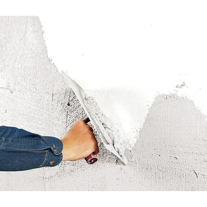 Knauf Dekoputz Mineralputz Diamant - Reinweiß, Körnung: 1 mm, 10 kg - Die Abbildung zeigt einen Bauarbeiter, der eine Wand mit einer Glättkelle verputzt, um eine glatte Oberfläche zu erzielen.