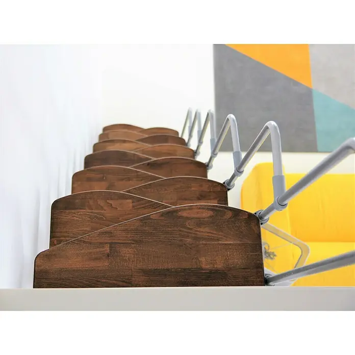 Minka Raumspartreppe Monaco - Breite: 60 cm, Grau, Farbe Stufen: Buche Walnuss gebeizt, Geschosshöhe: 294 cm - Nahaufnahme einer Holztreppe mit silbernem Geländer, die sich vor einer weißen Wand und einem farbenfrohen Kunstwerk befindet.