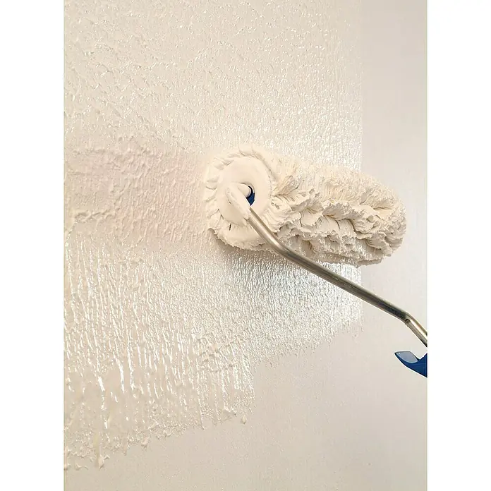 Knauf EasyPutz Dekoputz Extra fein - im Rezyklatgebinde - Weiß, Körnung: 0,5 mm, 20 kg, Konservierungsmittelfrei - Ein flauschiger Farbroller in Aktion, der weiße Farbe auf eine Wand aufträgt und eine interessante Textur erzeugt.