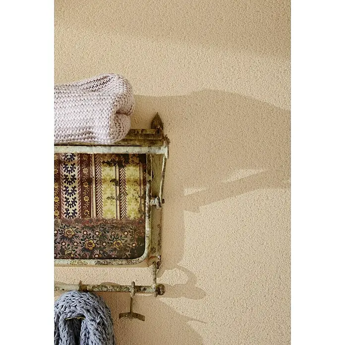 Knauf Putz-Abtönfarbe Compact Color - Terracotta, 6 g - Einrichten mit Stil: Antikes Wandregal mit gestrickten Textilien in sanften Farbtönen vor einer strukturierten Wand.