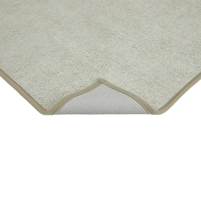 Badteppich Malibu - 60 x 100 cm, Beige, 100% Polyester - Nahaufnahme eines beigefarbenen Badteppichs mit strukturierter Oberfläche und braunem Rand, der eine weiche und einladende Textur zeigt.