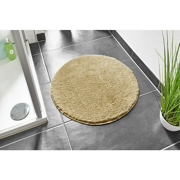 Badteppich Florida - 60 x 60 cm, Taupe, 100% Polyester - Runde, flauschige Badematte in Beige auf grauen Fliesen, neben Dusche und Zimmerpflanze. Komfort und Stil für Ihr Badezimmer.