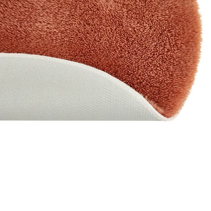 Badteppich Florida - 60 x 60 cm, Rostrot, 100% Polyester - Detailaufnahme eines weichen, terracottafarbenen runden Teppichs mit weißer Unterseite, der Komfort und Stil vereint.