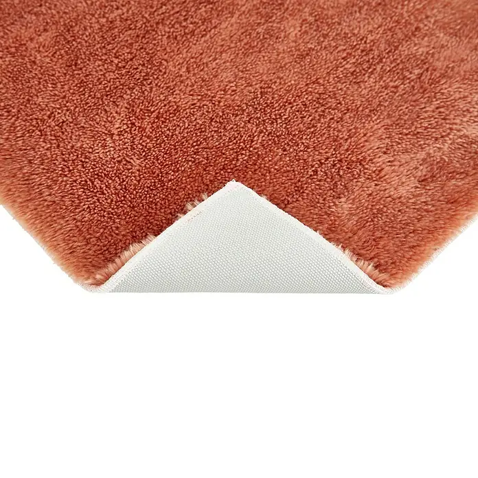Badteppich Florida - 50 x 80 cm, Rostrot, 100% Polyester - Detailansicht eines orangefarbenen Teppichs mit weicher Textur und weißer Unterseite, die die Qualität und das Material hervorhebt.
