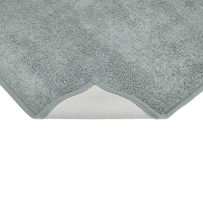 Badteppich Malibu - 60 x 100 cm, Grau, 100% Polyester - Nahaufnahme einer grauen Badematte mit weißer Rückseite und dezenter Umrandung. Das flauschige Material lädt zum Verweilen ein.