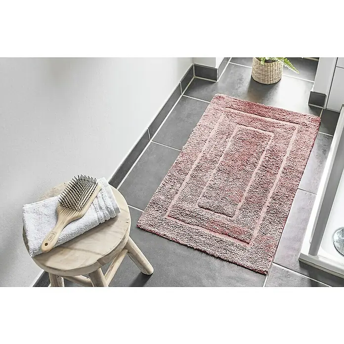 Badteppich Havanna - 50 x 80 cm, Rostrot, Border, 80% Baumwolle, 20% Polyester - Ein rechteckiger, rosa Badteppich mit konzentrischen Rechtecken liegt auf grauem Fliesenboden in einem Badezimmer.