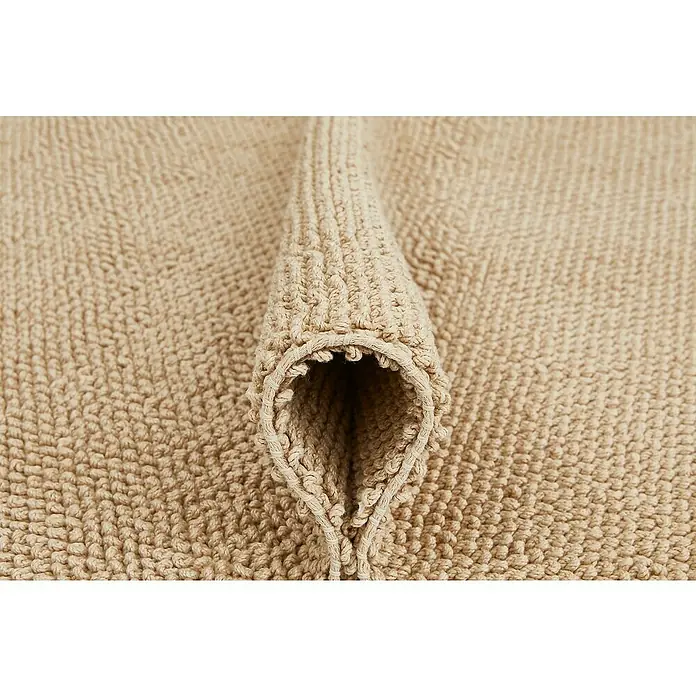 Badteppich Atlanta - 50 x 80 cm, Beige, 100% Baumwolle - Nahaufnahme eines beigen Badteppichs mit interessanter Textur und einer gerollten Kante, die die hochwertige Verarbeitung betont.