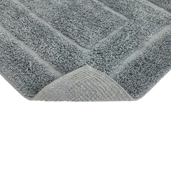 Badteppich Havanna - 50 x 80 cm, Grau, Border, 80% Baumwolle, 20% Polyester - Detailaufnahme einer grauen Badematte mit strukturiertem Muster und gewendeter Ecke, die die Unterseite zeigt.