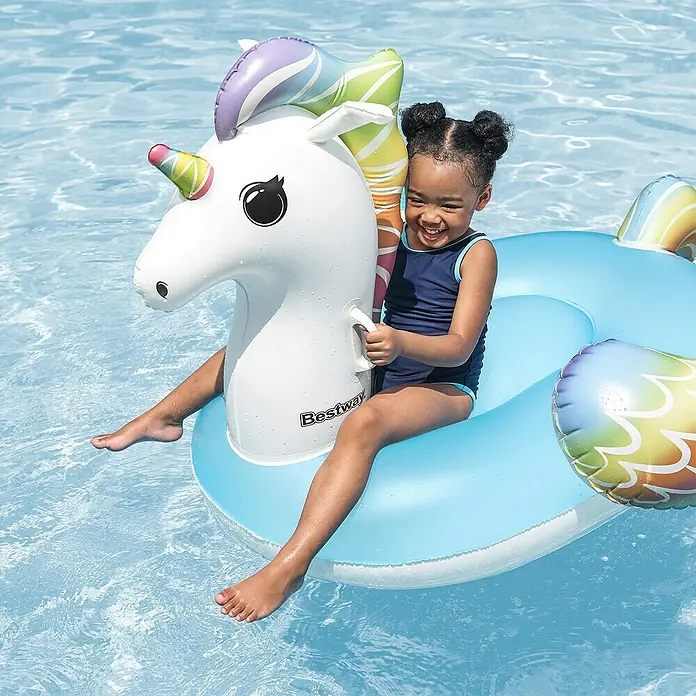 Bestway Schwimmtier Fantasy Unicorn - 110 x 163 x 95,5 cm - Ein lächelndes Mädchen genießt den Sommer auf einem aufblasbaren Bestway Einhorn-Schwimmtier im Pool.
