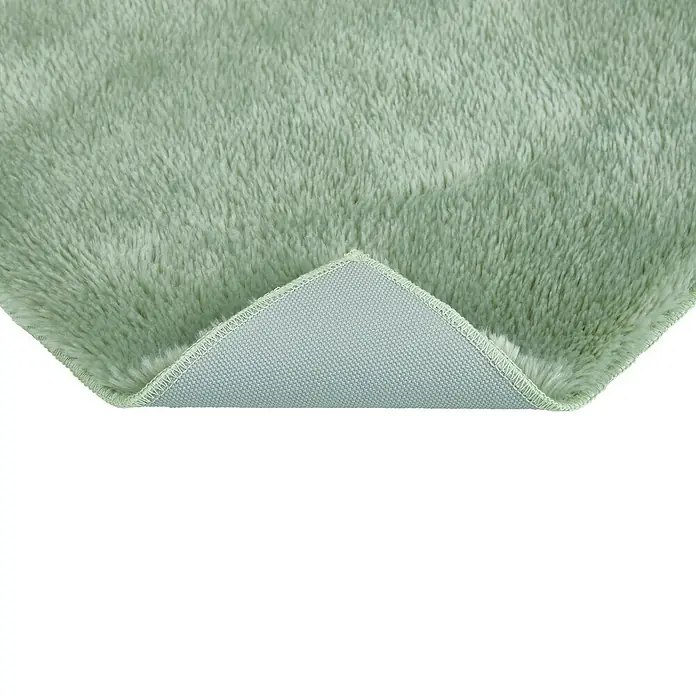 Badteppich Florida - 50 x 80 cm, Salbei, 100% Polyester - Nahaufnahme eines mintgrünen, flauschigen Teppichs, der teilweise umgeschlagen ist, um die Unterseite zu zeigen.
