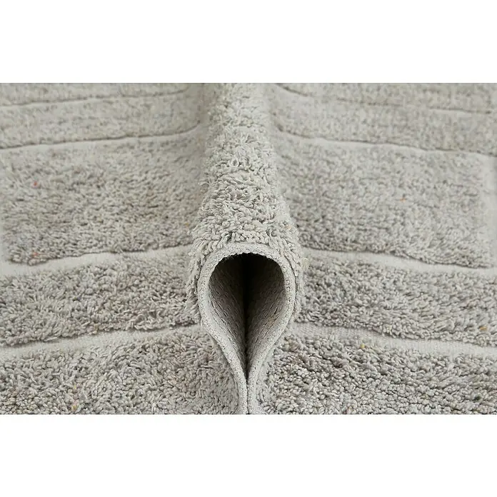 Badteppich Havanna - 50 x 80 cm, Taupe, Border, 80% Baumwolle, 20% Polyester - Nahaufnahme eines grauen Teppichs mit Streifenmuster, der in der Mitte gefaltet ist und eine interessante Textur und Form zeigt.