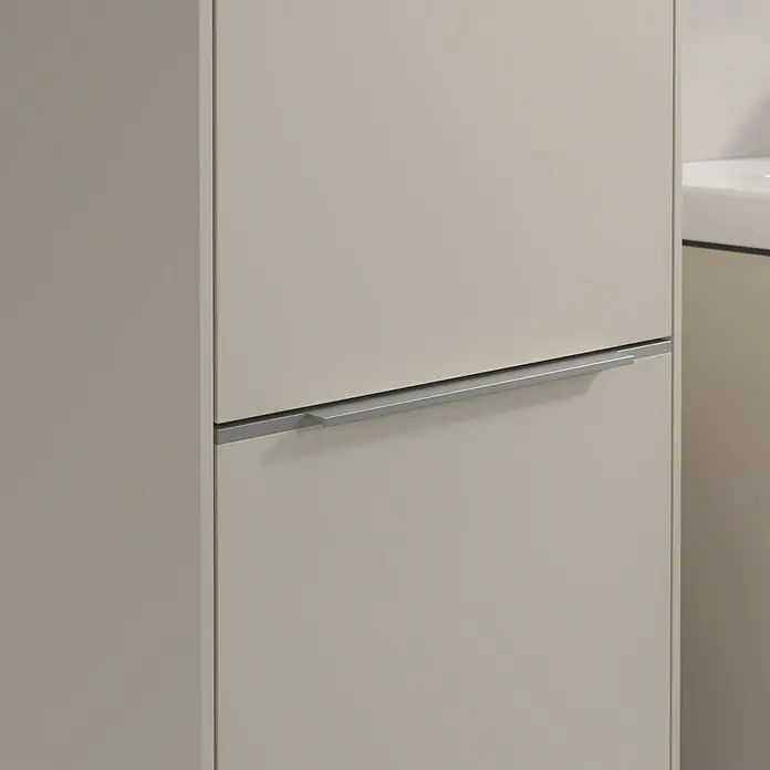Villeroy & Boch Subway 3.0 Hochschrank - B x T x H: 40 x 36,2 x 171 cm, 2x Tür, Cashmere Grey, Farbe Griff: Aluminium glänzend, DIN Anschlag: Links - Nahaufnahme eines modernen cremefarbenen Badschranks mit einem langen, schmalen silbernen Griff. Das Möbelstück hat eine glatte Oberfläche.