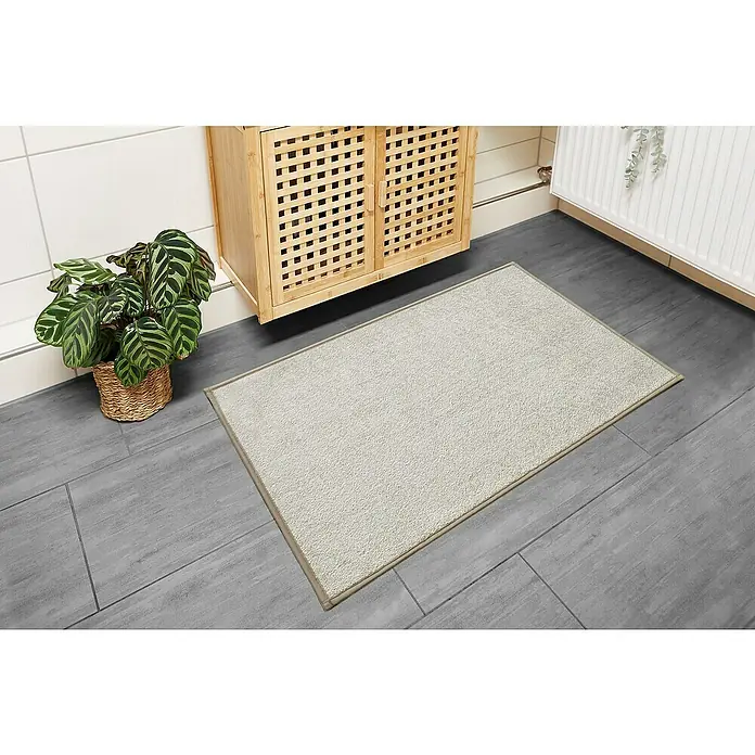 Badteppich Malibu - 60 x 100 cm, Beige, 100% Polyester - Badezimmer mit hellgrauer Badematte, Holzschrank und Zimmerpflanze für eine gemütliche Atmosphäre.