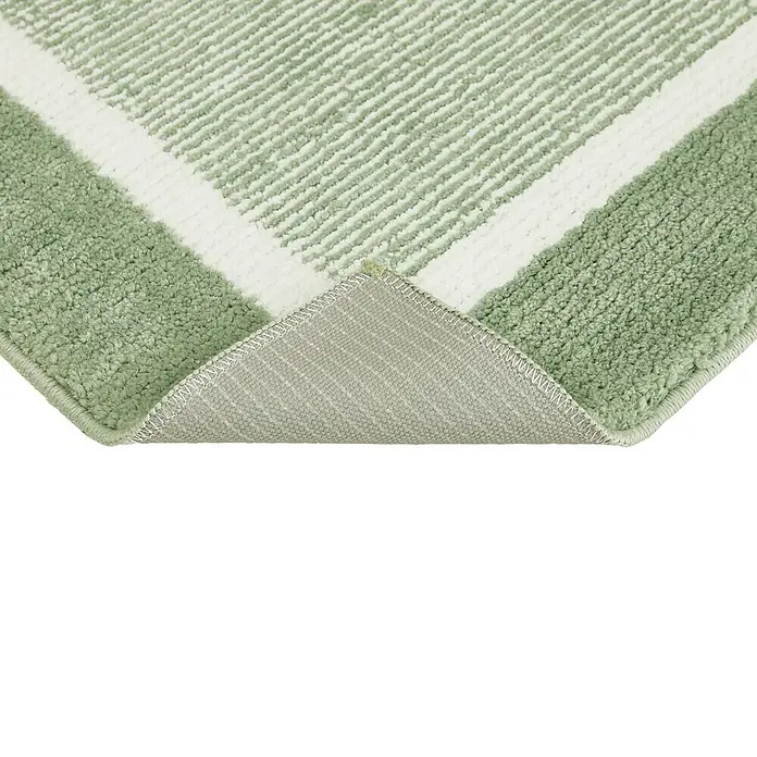 Badteppich Maui - 60 x 100 cm, Salbei, 100% Polyester - Nahaufnahme eines hellgrünen Teppichs mit weißen Streifen und grauer Rückseite, der aufgerollt ist und Textur und Detailreichtum zeigt.
