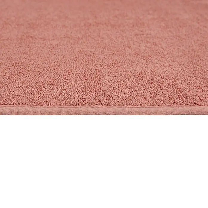Badteppich Malibu - 60 x 100 cm, Rostrot, 100% Polyester - Nahaufnahme eines rosa Badteppichs, der weich und flauschig aussieht. Der Teppich hat eine schlichte Bordüre und eine angenehme Textur.