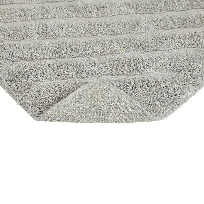 Badteppich Havanna - 50 x 80 cm, Taupe, Stripe, 80% Baumwolle, 20% Polyester - Detailaufnahme eines grauen Badteppichs mit gewebter Textur und umgeschlagener Ecke, die die Rückseite zeigt.