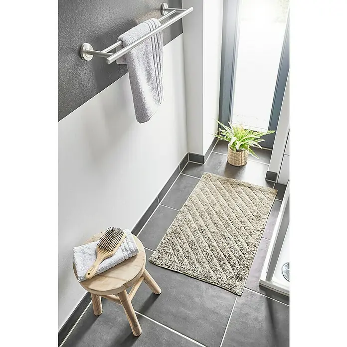 Badteppich Havanna - 50 x 80 cm, Beige, Stripe, 80% Baumwolle, 20% Polyester - Das Bild zeigt eine Badematte mit diagonalem Muster in einem Badezimmer. Die Badematte ist beige und liegt auf grauen Fliesen.