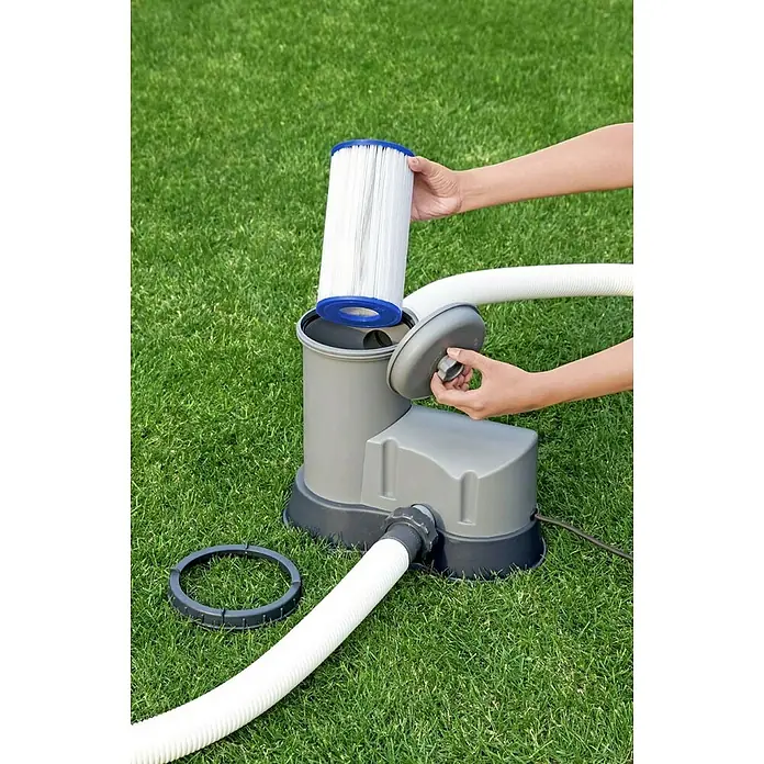 Bestway Filterkartusche - Filterleistung: 5.678 l/h - Eine graue Poolfilterpumpe mit Filter und Schläuchen steht auf einer grünen Rasenfläche. Die Pumpe ist mit einem neuen Filter versehen.